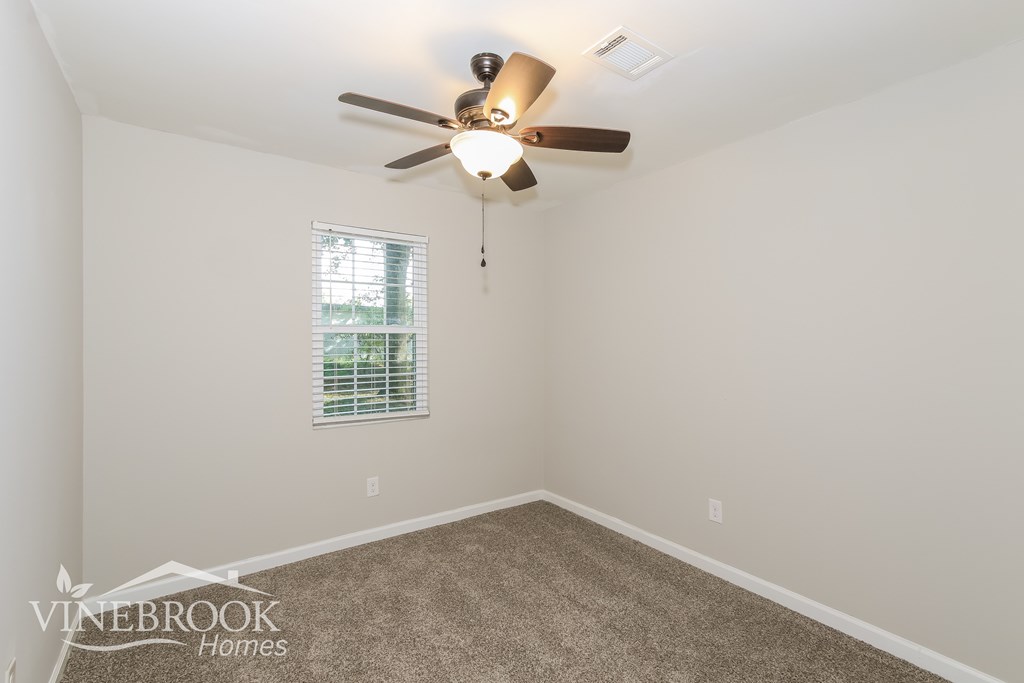 a bedroom with a ceiling fan and a carpet